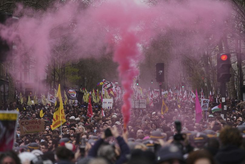 Um fumo cor-de-rosa é disparado enquanto as pessoas marcham durante o dia internacional contra o racismo e o fascismo, em Paris, sábado, 22 de março de 2025
